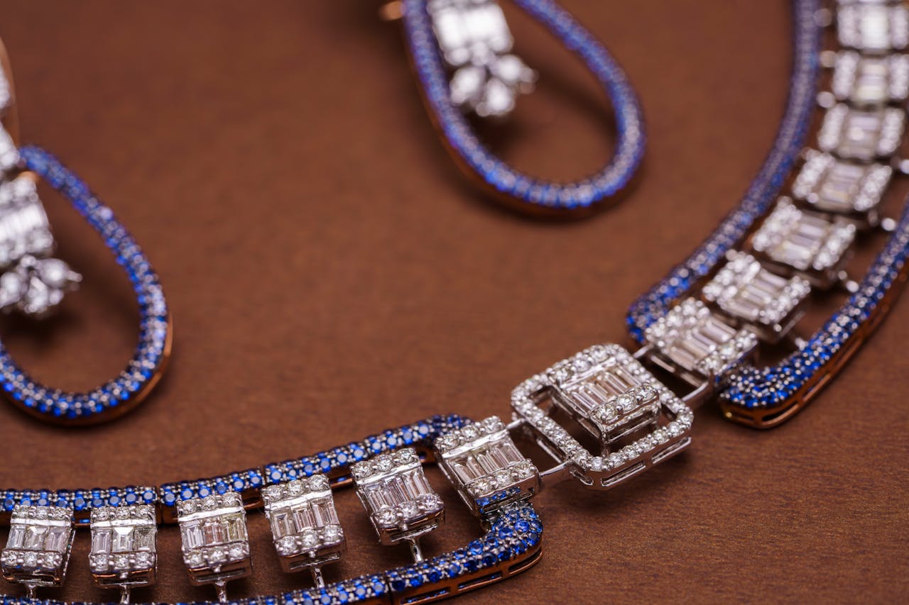 Close-up of an exquisite blue sapphire and diamond necklace and earrings against a brown background.